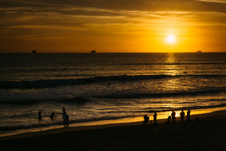 People on the beach and sunset over the Pacific Ocean in Huntington Beach, California.の写真素材