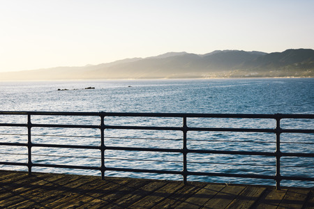 Fence on the Santa Monica Pier and view of mountains and the Pacific Ocean, in Santa Monica,...