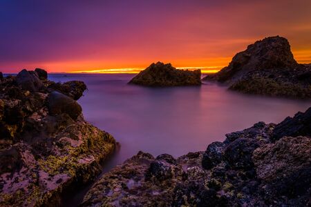 Long exposure of waves and rocks in the Pacific Ocean at sunset, at Woods Cove, in Laguna Beach, California.の写真素材