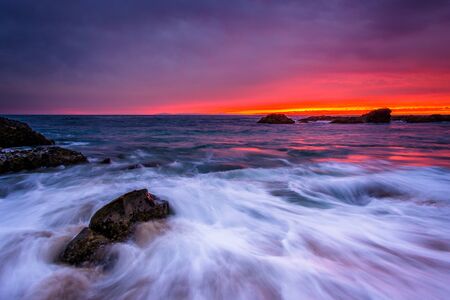Waves and rocks in the Pacific Ocean at sunset, at Woods Cove, in Laguna Beach, California.の写真素材
