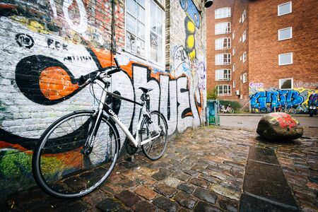 A parked bicycle and graffiti in Christiania, in Christianshavn, Copenhagen, Denmark.のeditorial素材