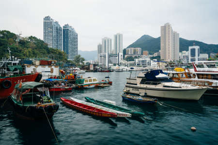 Boats docked at Ap Lei Chau and view of skyscrapers and mountains in Hong Kong, Hong Kong.のeditorial素材