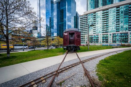 Railroad car at Roundhouse Park and modern buildings in downtown Toronto, Ontario.のeditorial素材