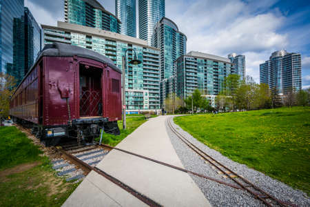 Railroad car at Roundhouse Park and modern buildings in downtown Toronto, Ontario.
