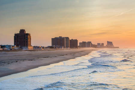 Waves in the Atlantic Ocean and buildings at sunrise, in Ventnor City, New Jersey.の写真素材