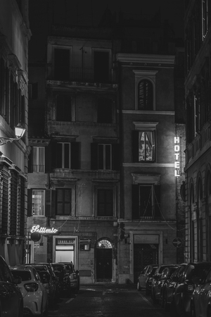 A narrow street and hotel sign at night in Rome, Italyの写真素材
