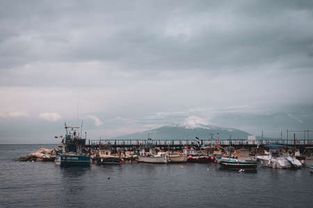 Boats in the water, and view of Mount Vesuvius covered in snow, Sorrento, Campania, Italy