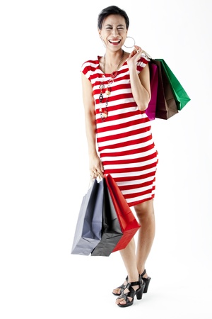 Full length of woman in red stripes dress carrying shopping bags isolated on whiteの写真素材
