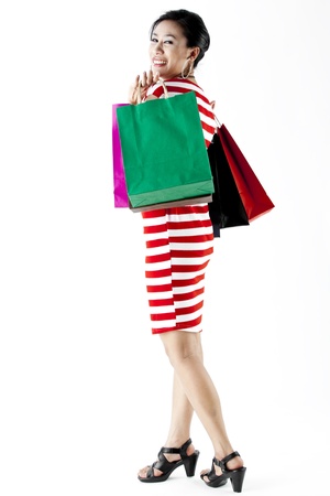 Full length of woman in red stripes dress carrying shopping bags isolated on whiteの写真素材
