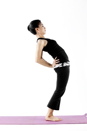 Asian female practising yoga while bending backwardsの写真素材