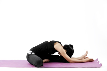 Asian female practising yoga in one legged forward bend poseの写真素材