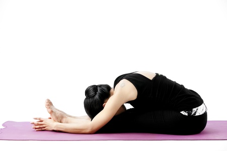 Asian female practising yoga in seated forward bend poseの写真素材