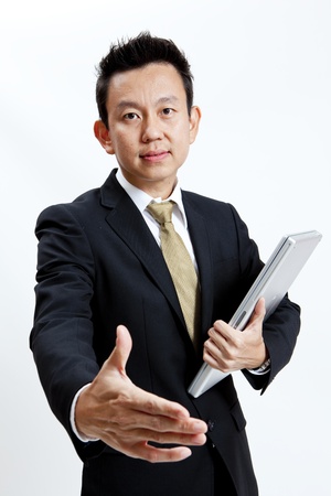 Businessman standing with laptop while offering handshake isolated on white backgroundの写真素材