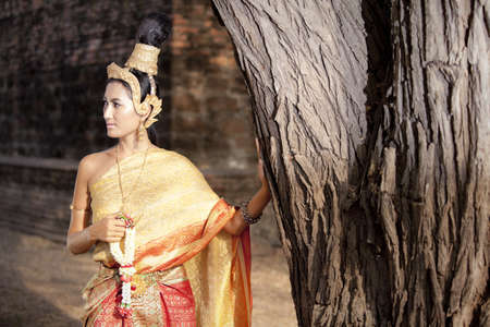Woman in traditional Thai clothings posing next to a treeの写真素材