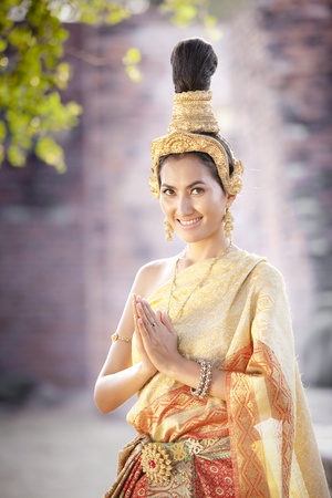 Thai woman in thai dress greets with the thai temple backgroundの写真素材