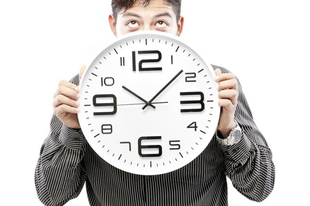 Close-up of a businessman holding a clock with a suspicious lookの写真素材