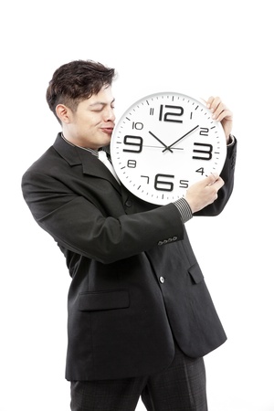 Close-up of a young businessman with analog clock on white backgroundの写真素材