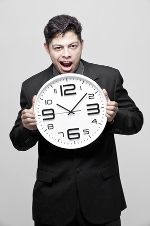 Close-up of a young businessman with analog clockの写真素材