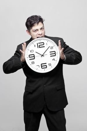 Close-up of a young businessman with analog clock