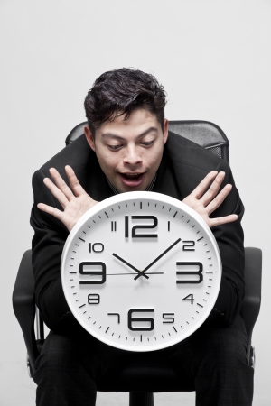 Close-up of a young businessman with analog clockの写真素材
