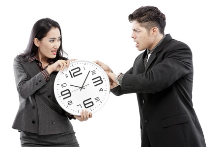 Businessman and businesswoman fighting over a wall clockの写真素材