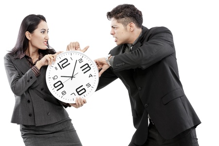 Businessman and businesswoman fighting over a wall clockの写真素材