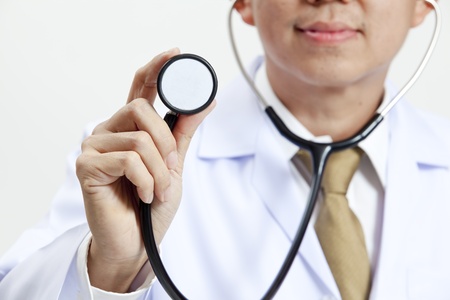Doctor holding up a stethoscope isolated on white backgroundの写真素材