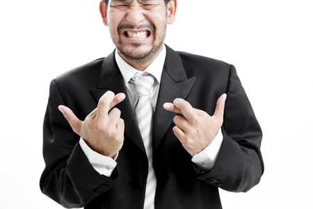 Businessman in suit and tie with fingers crossed against white backgroundの写真素材