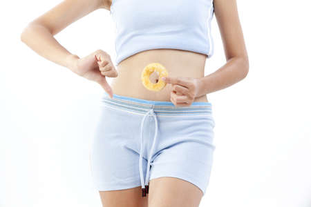 Beautiful asian lady holding a doughnut and give a thumbs down の写真素材