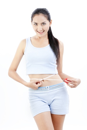 Beautiful asian lady measuring her tummyの写真素材