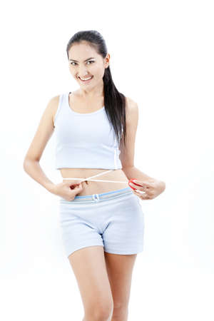 Beautiful asian lady measuring her tummyの写真素材
