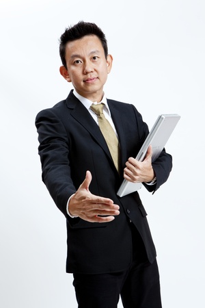 Businessman is giving a handshake while holding his laptopの写真素材
