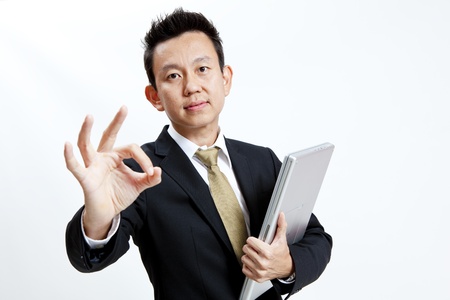 Businessman is showing hand gesture while holding his laptopの写真素材