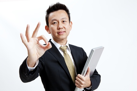 Businessman is showing hand gesture while holding his laptopの写真素材