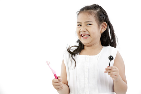 A young Asian girl posing with a toothbrush and lollipopの写真素材