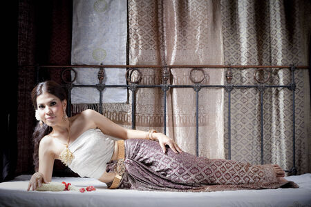 Woman in traditional clothes lying sideways on bedの写真素材