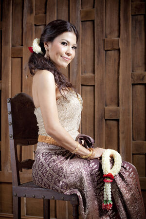 Woman in traditional clothes sitting while holding flower garlandの写真素材