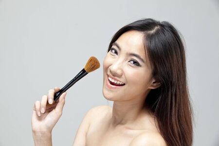 Young woman holding makeup brush and smilingの写真素材
