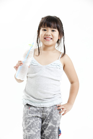 Girl holding a water bottle and smiling at the cameraの写真素材