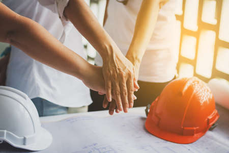 Business women and engineer working hands of business people joined hands together in office meeting. Teamwork Concept and commitment to success.の写真素材
