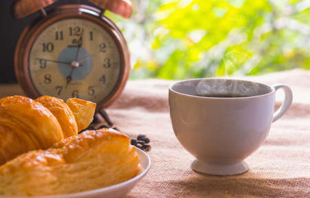 Coffee and bread Breakfast at 7.00 am with green leafy background.の写真素材
