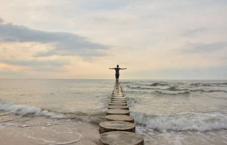 A lonely person stands on the edge of a cliff and looks at the sea