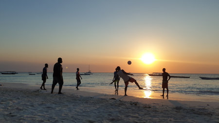The silhouettes of black men playing ball on the beach on Zanzibar during sunset.の写真素材