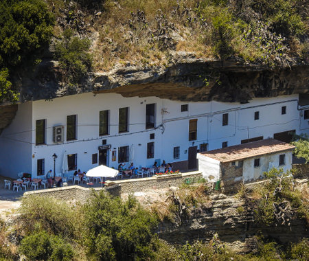 People have dinner under a huge hanging rock in Setenil de las Bodegas, Spainの写真素材
