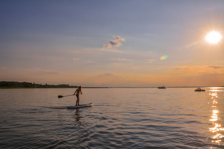 Young boy rowing on a sup in the sunsetの写真素材