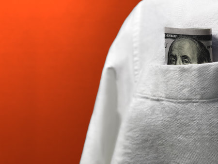 Close-up of one hundred dollar bill in pocket of white shirtの写真素材