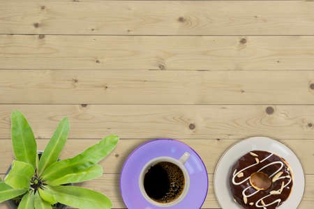 Overhead view of doughnut and a cup of strong black filter or espresso coffee on a rustic wood tableの写真素材