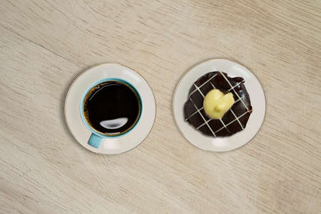 Overhead view of doughnut and a cup of strong black filter or espresso coffee on a rustic wood tableの写真素材