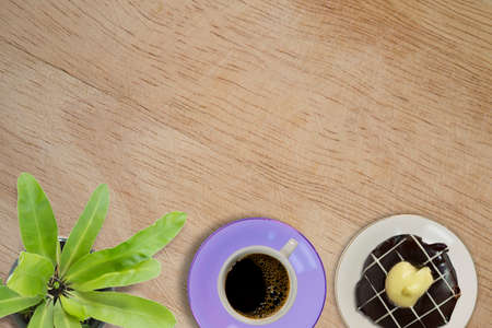 Overhead view of doughnut and a cup of strong black filter or espresso coffee on a rustic wood tableの写真素材