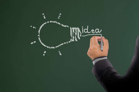 Businessman drawing light bulb on board. Light bulb idea for inspiration creativeの写真素材